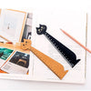 A wooden drawing ruler shaped like a cute cartoon cat is displayed on white paper with framed artwork.