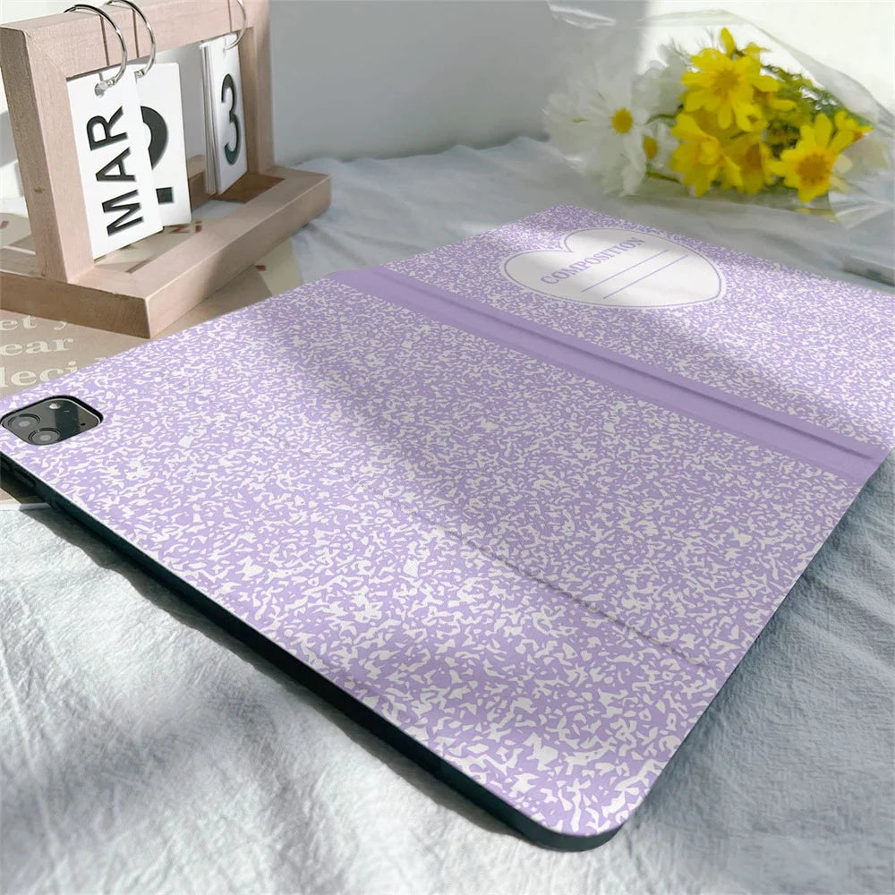 A purple composition book cover with a pencil holder resting on a white sheet.