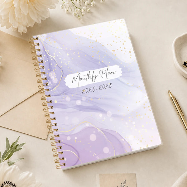 Aesthetic A5 monthly planner featuring a purple marble design with gold accents and spiral binding on a light background.