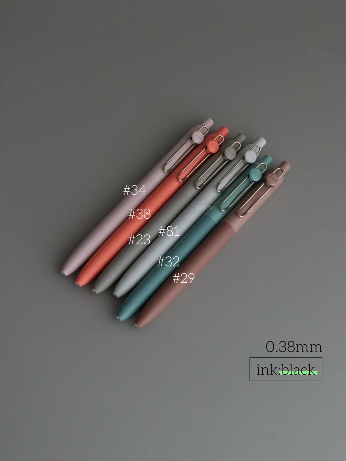 A collection of precision gel pens in various shades of pink, red, and blue, shown diagonally on a gray surface.
