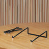 A black foldable aluminum laptop stand with non-slip grips resting on a wooden surface.
