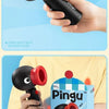 A hand holds a black and red Pingu penguin handheld fan with a rotating head against a light blue background.