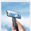 Eine Hand hält einen faltbaren Aluminium-Handyhalter, der eine bergige Landschaft auf einem Smartphone-Bildschirm zeigt.