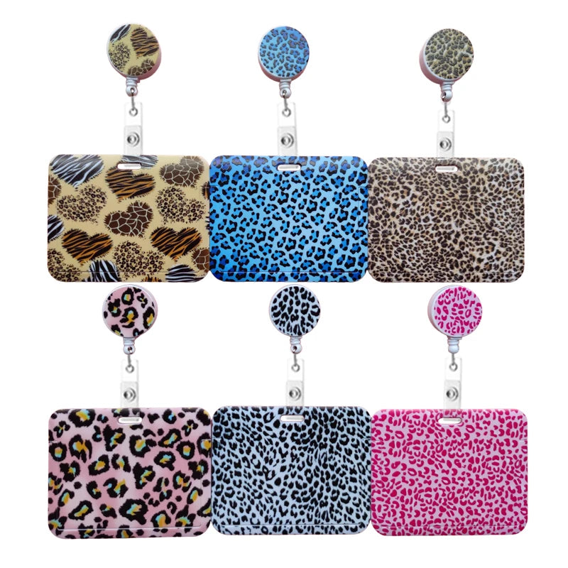 A collection of pink, blue, and leopard print retractable card holders with metal clips.