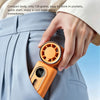 A hand is holding an orange portable clip-on handheld cooling fan, which is inserted into a gray suit jacket pocket.