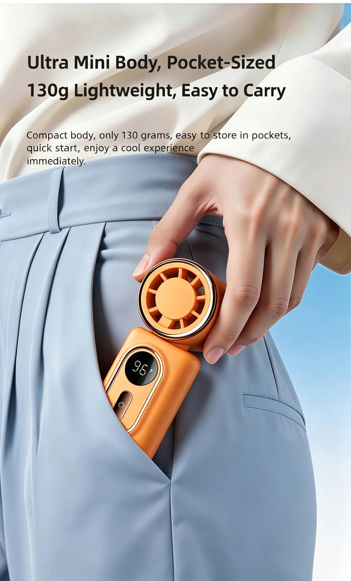 A hand is holding an orange portable clip-on handheld cooling fan, which is inserted into a gray suit jacket pocket.