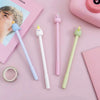 A collection of cute cartoon fruit gel pens in various pastel colors and shapes arranged on a pink background.