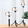 A silver selfie stick tripod with a smartphone mounted on top, featuring a fill light and wireless remote.