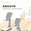A white foldable desktop phone stand with a metal clamp is shown on a wooden surface.