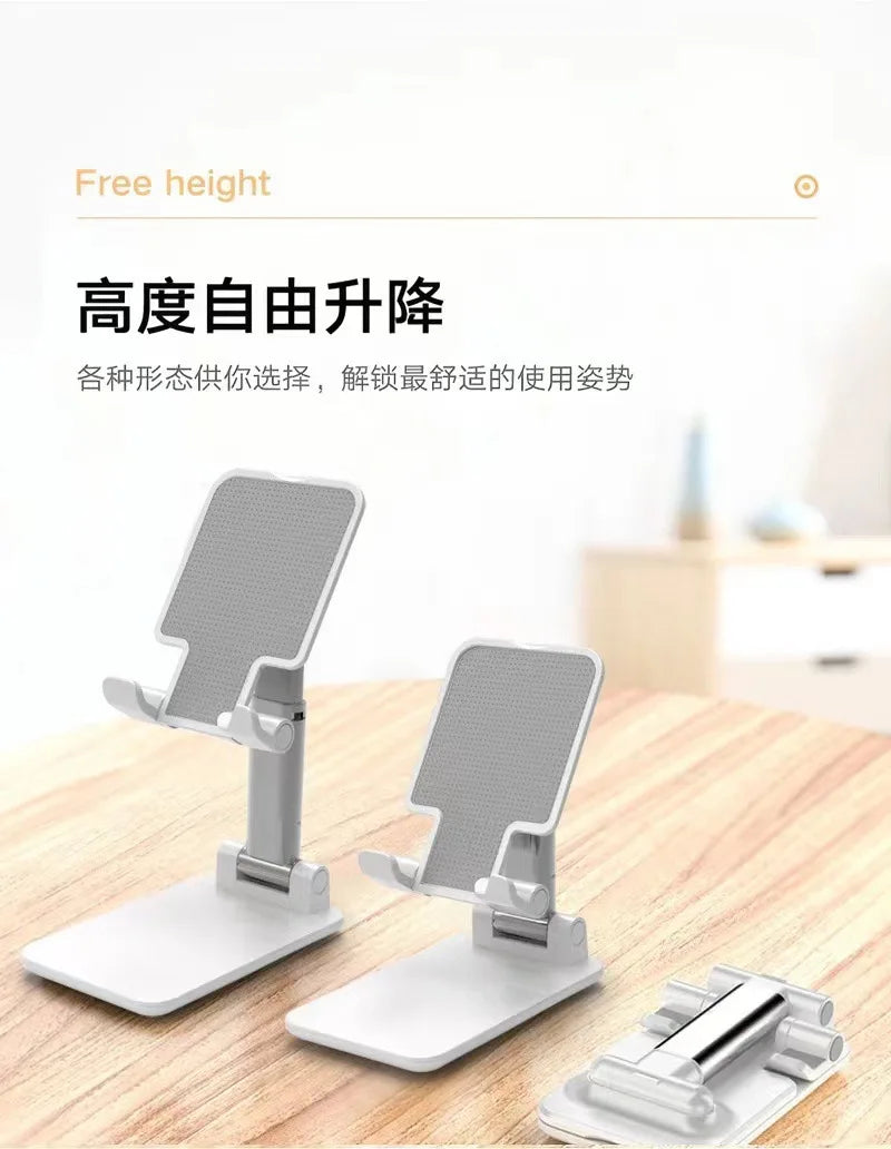 A white foldable desktop phone stand with a metal clamp is shown on a wooden surface.