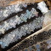 Decorative silver stamping lace tape featuring floral patterns on a dark wooden surface.