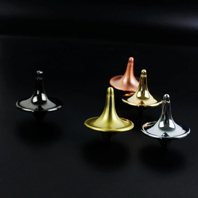 A collection of metal hand spinning tops in various colors including silver, gold, and rose gold displayed on a dark surface.