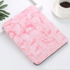 A pink marble patterned skin for an iPad Pro placed on a white surface next to a cup of coffee.