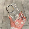 A hand holds a clear holographic gradient phone case for an iPhone featuring a cross design.