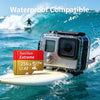 A silver camera is mounted on a surfboard in the ocean water with a wave in the background.