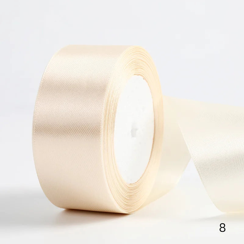 A roll of pale beige satin ribbon used for gift wrapping and DIY crafts.