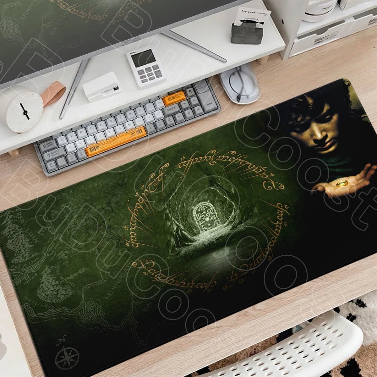 A dark green gaming mouse pad featuring Lord of the Rings imagery placed on a wooden desk with a keyboard and mouse.