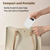 A hand is placing a white portable power bank with a digital display into a beige handbag.