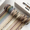 A collection of vintage colored washi tape rolls displayed on a white box, showing various earthy and muted tones.