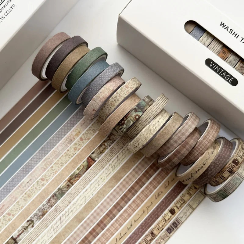 A collection of vintage colored washi tape rolls displayed on a white box, showing various earthy and muted tones.