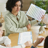 A woman is teaching children how to count using a 120-point number line math posters set.