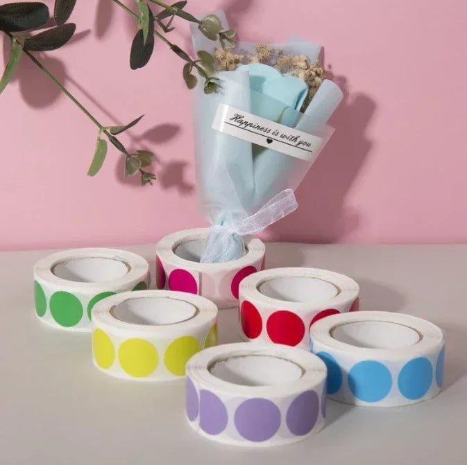 A collection of round dot labels in various colors like pink, green, yellow, and purple are displayed on a white surface.