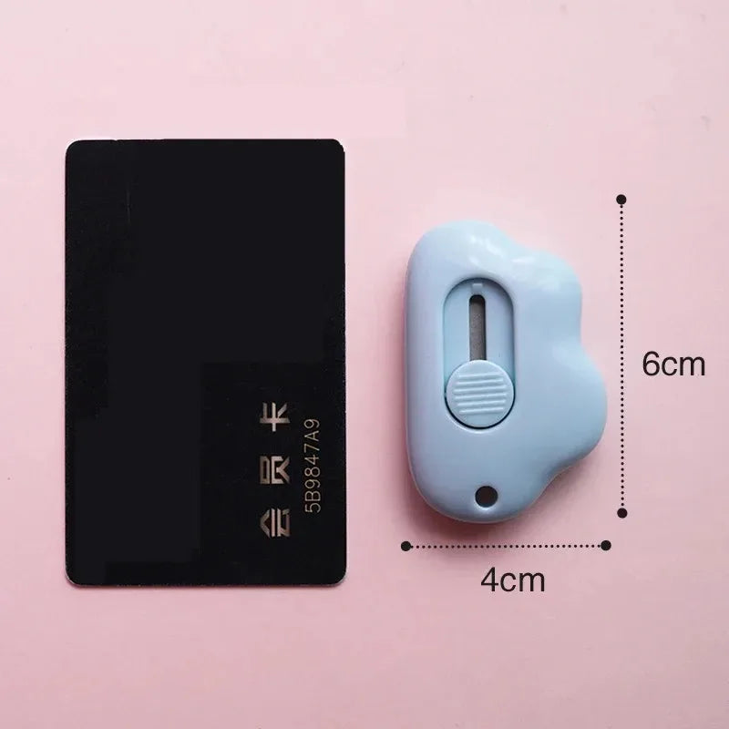 A black utility knife and a light blue, ergonomic opening tool are shown against a pink background.