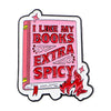 A pink enamel lapel pin shaped like a book with red text that reads I LIKE MY BOOKS EXTRA SPICY