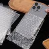 A smartphone is wrapped in clear bubble wrap for protection, resting on a wooden surface.