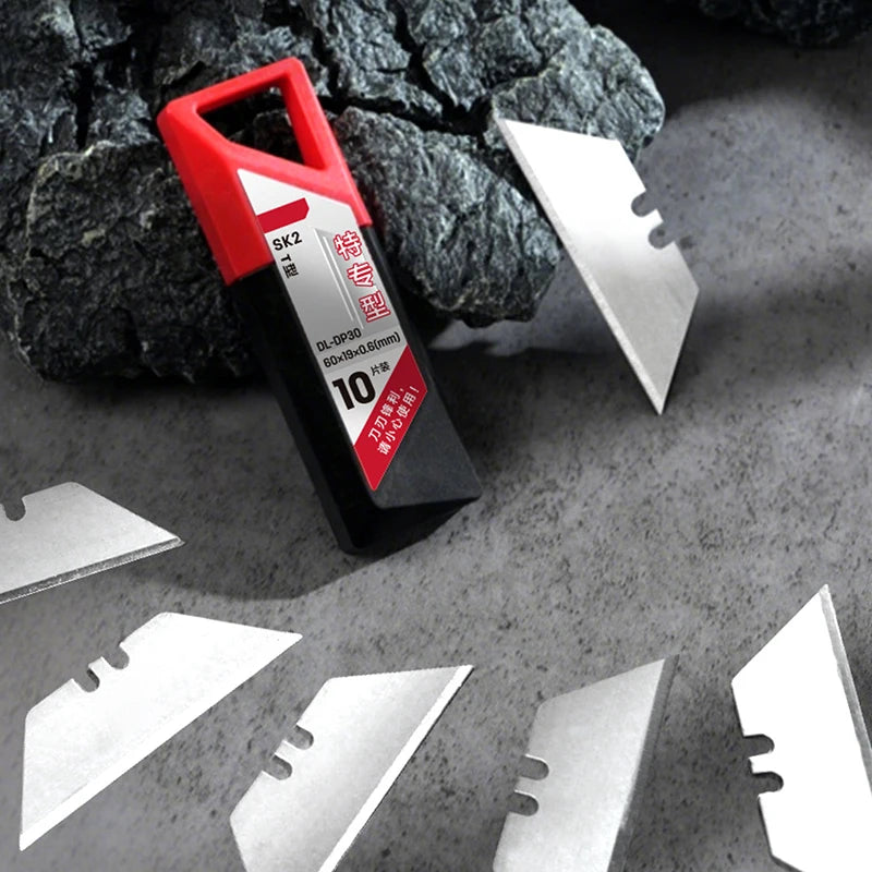 A red and black precision T-shape knife blade set is displayed on a gray surface with several silver metal blades scattered a