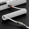 Langes, aufgewickeltes USB-C-Tastaturkabel mit schwarzem Anschluss und weißer Isolierung auf dunkler Oberfläche