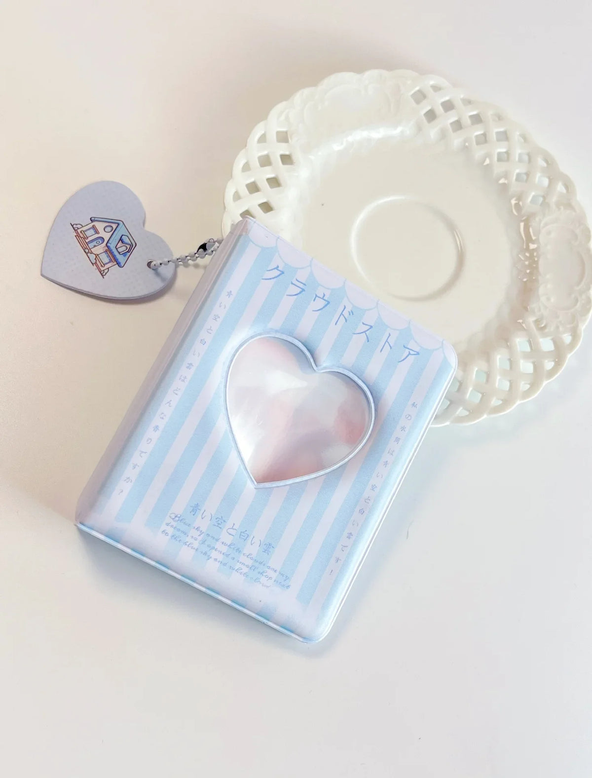 A clear binder with a heart-shaped window is shown next to a white lace-edged plate.