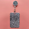 A black leopard print retractable card holder clip with a circular badge holder attached.