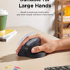 A hand is holding a black ergonomic wireless vertical mouse on a desk, demonstrating its grip for large hands.