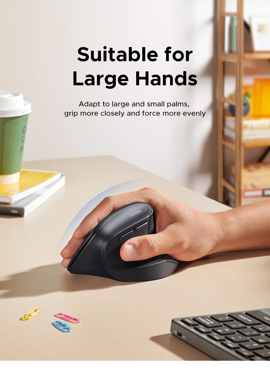 A hand is holding a black ergonomic wireless vertical mouse on a desk, demonstrating its grip for large hands.