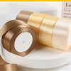 Rolls of satin ribbon in beige and gold colors displayed on a white surface.