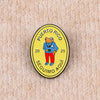 A yellow enamel pin featuring an orange frog wearing a blue shirt and red pants, with the text Puerto Rico and Seguimo Aquí.