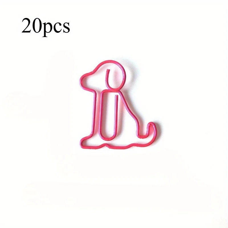 A pink paper clip shaped like a sitting dog, used as a cute desk organizer.