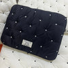 A dark navy padded laptop sleeve case resting on a white quilted surface.