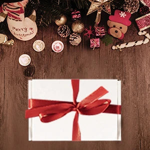A festive arrangement of Christmas decorations and a red ribbon tied around a white gift box.