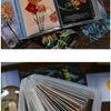 A stack of A6 photo storage booklets featuring floral and nature-themed designs.