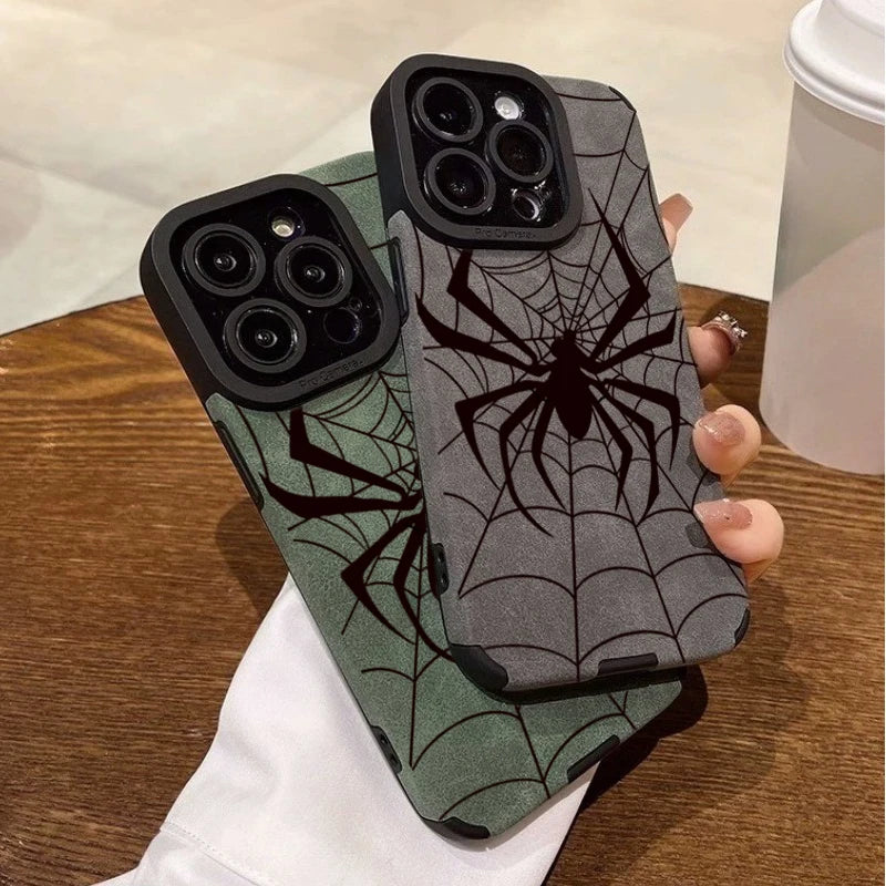 A dark green phone case featuring a black spider web design, held by a hand.