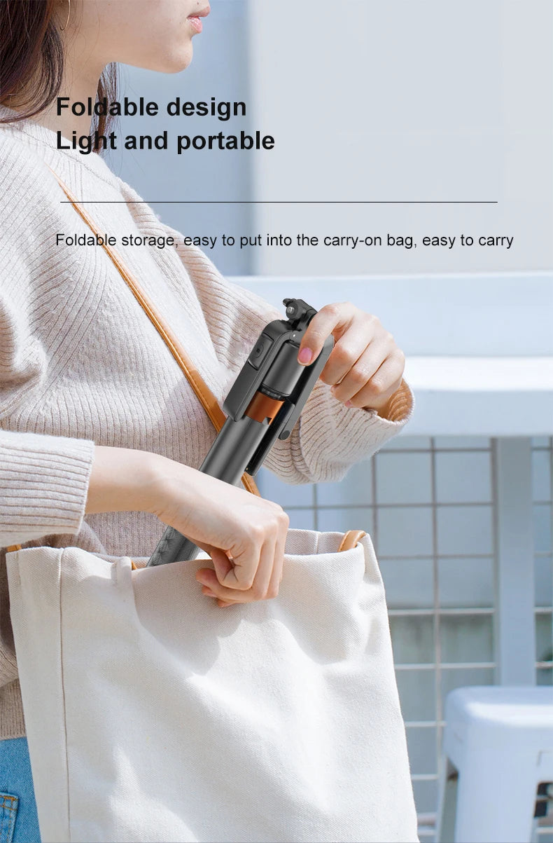 A person is holding a black AI face tracking smartphone tripod with Bluetooth remote in a white tote bag.