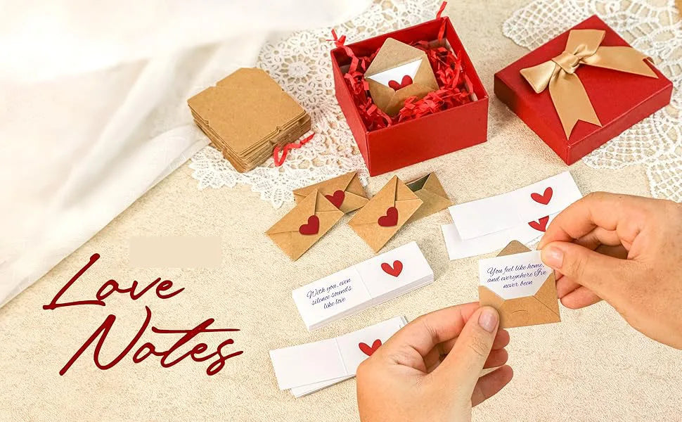 A collection of red and kraft paper note cards and envelopes with hearts, arranged on a beige fabric surface.