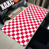 A red and white checkered desk mat is placed on a gray desk next to a keyboard and gaming controller.