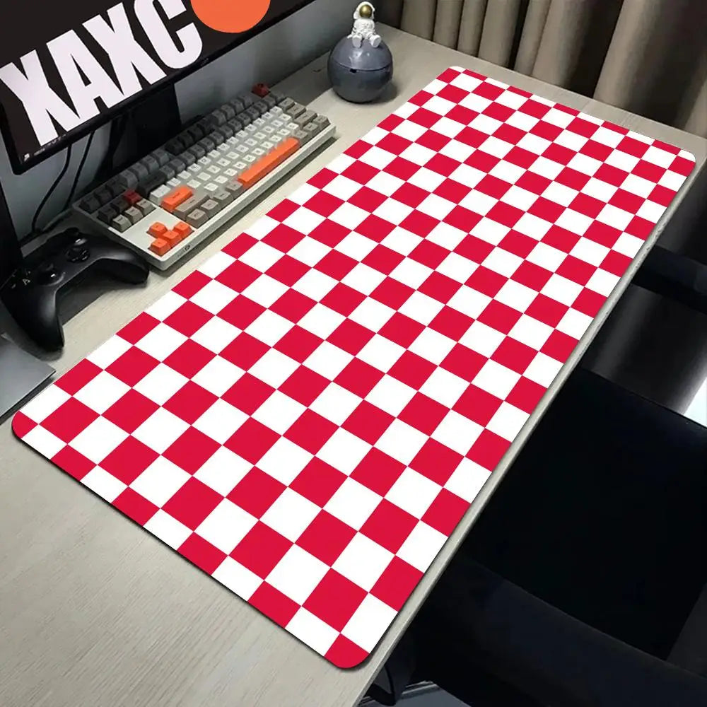 A red and white checkered desk mat is placed on a gray desk next to a keyboard and gaming controller.