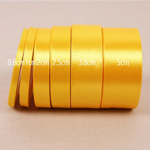 A roll of gold yellow satin ribbon with various widths measured in centimeters.