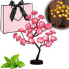 Pink rose tree LED night light with pink blossoms and green leaves displayed next to a pink gift bag.