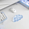 A white ergonomic cloud wrist rest is shown next to a white computer mouse and a keyboard on a white desk.