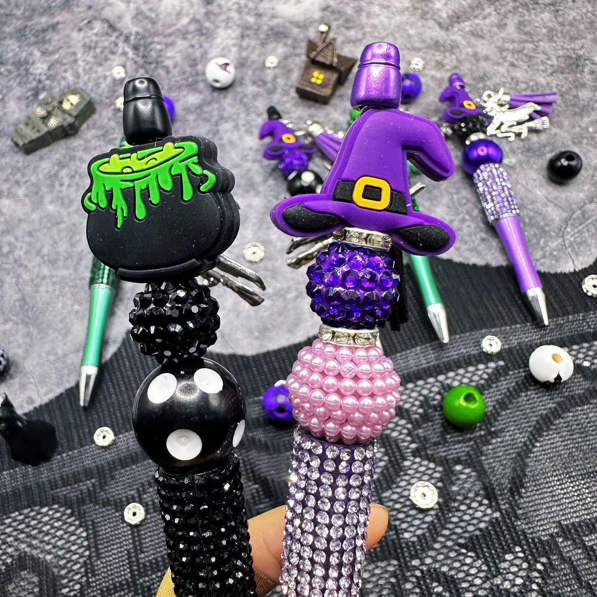 A set of Halloween DIY bead pens featuring witch charms and purple and black beads.
